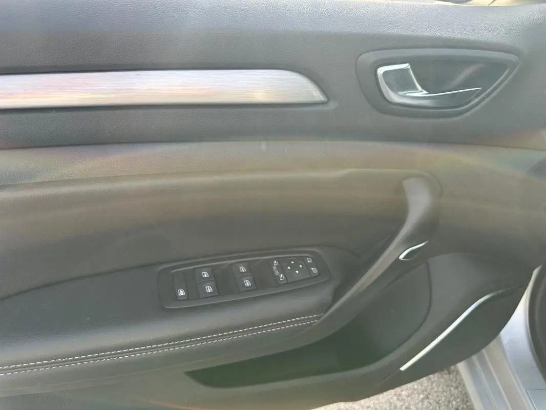 Gros plan sur la porte côté conducteur de la Renault Mégane Break gris clair, avec commandes électriques et finition cuir.