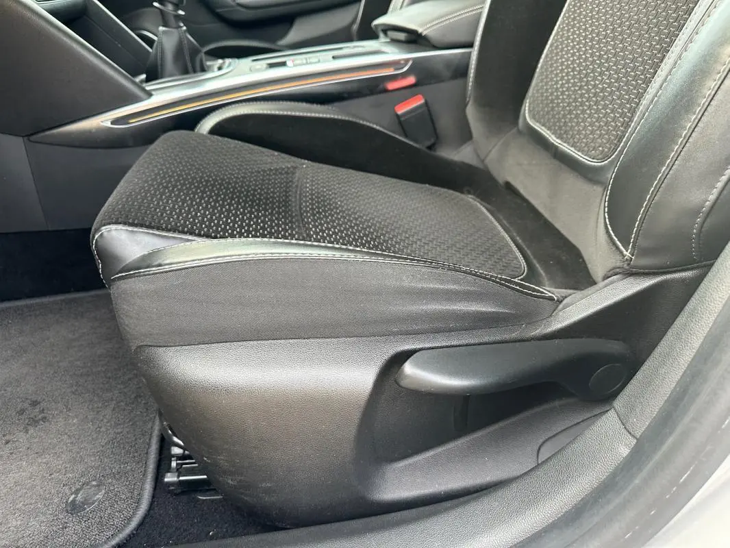 Gros plan sur le siège conducteur noir en tissu et cuir du Renault Mégane Break IV gris clair, intérieur soigné.