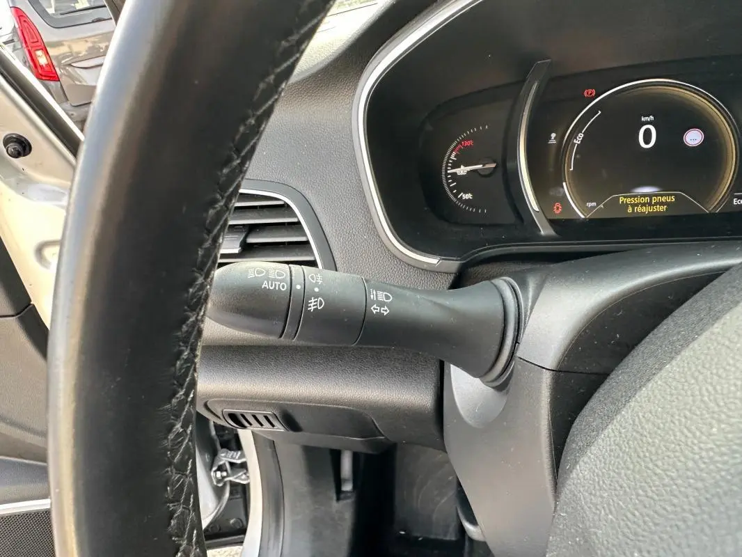 Vue rapprochée du tableau de bord et du volant cuir d'une Renault Mégane Break gris clair, affichage tête haute actif.