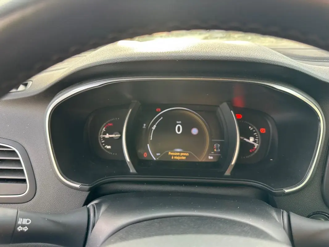Tableau de bord numérique de Renault Mégane Break gris clair, affichant la vitesse à 0 km/h et alertes visibles.