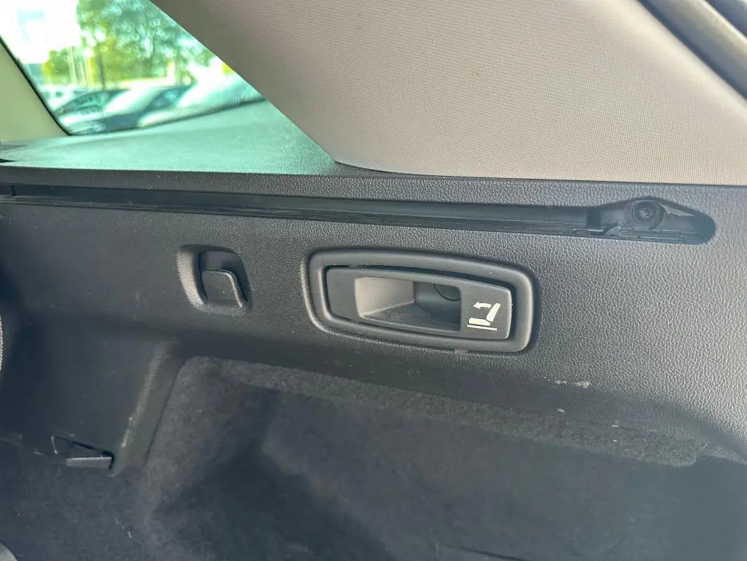 Gros plan sur la poignée de rabattement des sièges arrière dans le coffre d'une Renault Mégane Break gris clair.