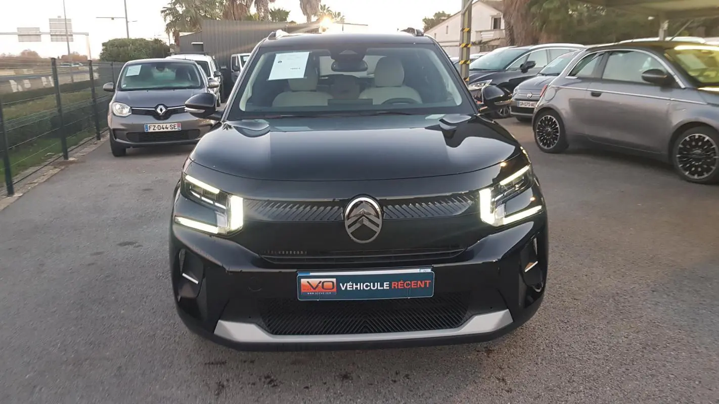 Citroën C3 noir vue de face avec feux LED allumés et barres de toit visibles sur un parking extérieur.