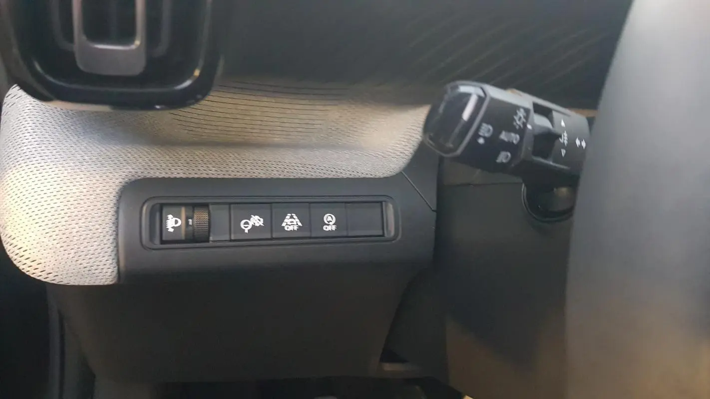Détail des commandes d’assistance et éclairage côté gauche du volant dans l’habitacle d’une Citroën C3 noire.