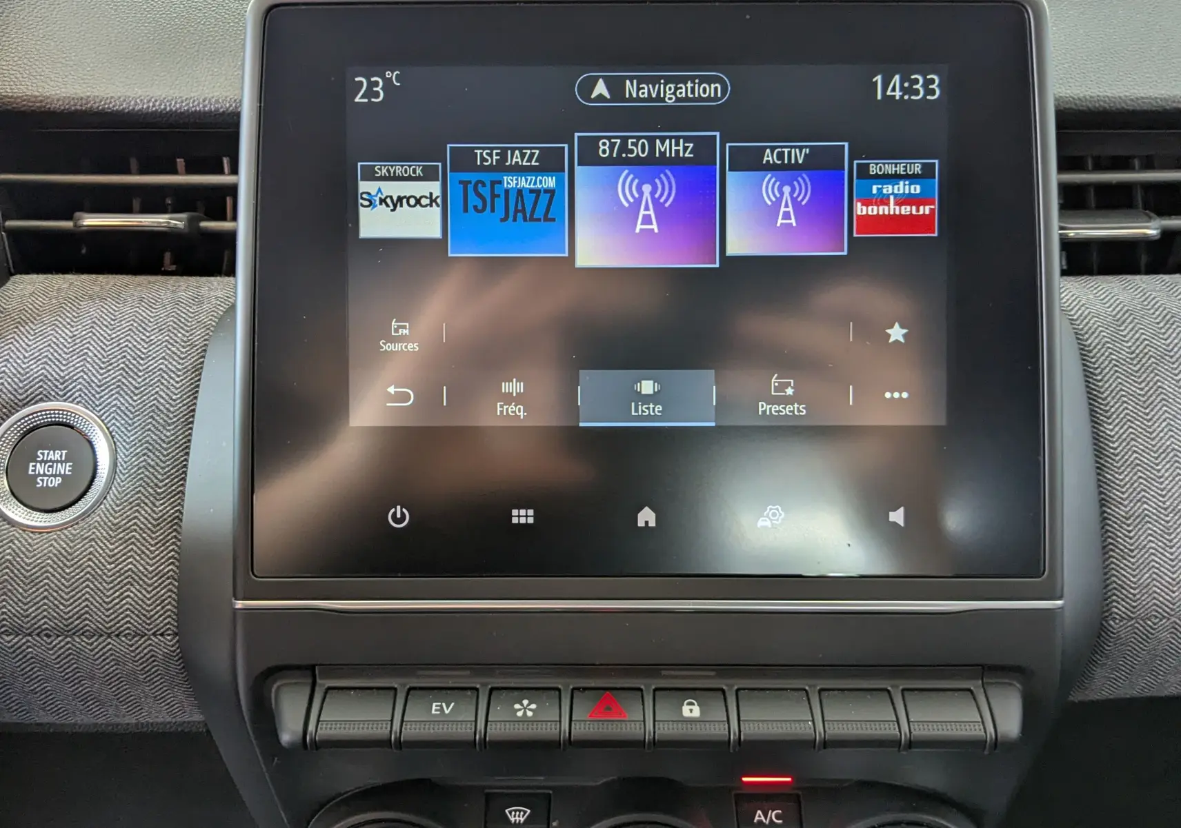 Écran tactile central de la Renault Clio V E-Tech gris schiste, affichant les stations radio avec bouton Start Engine à gauche.