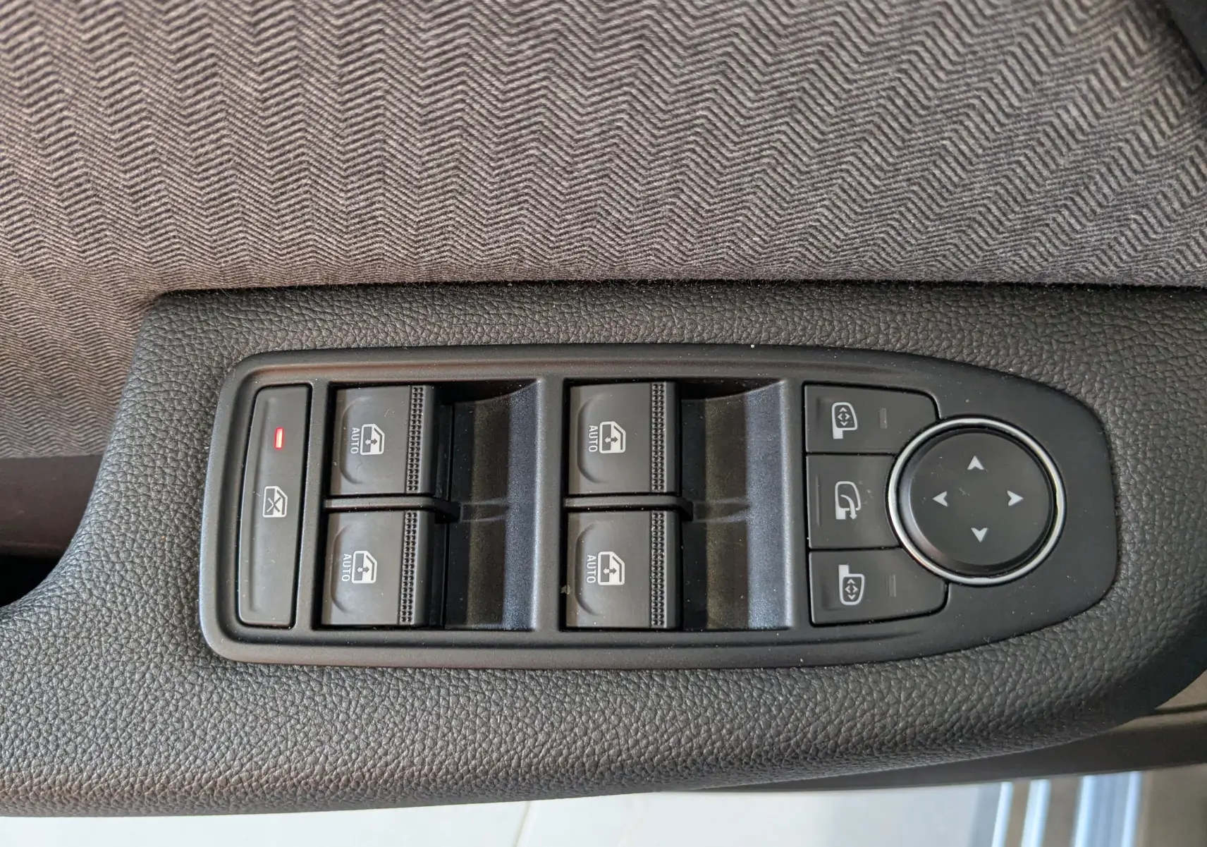 Vue rapprochée des commandes de lève-vitres et réglages des rétroviseurs sur la porte côté conducteur d’une Renault Clio gris schiste.