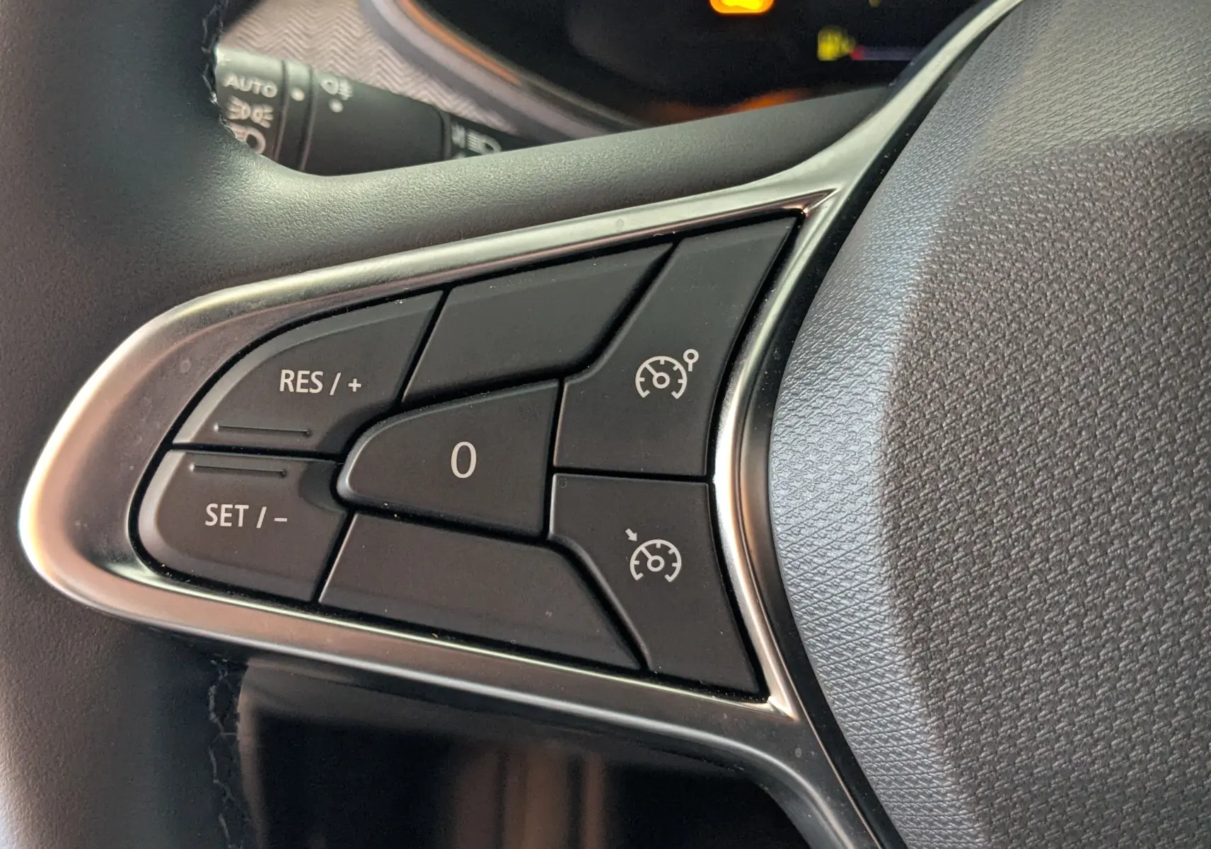 Gros plan sur les commandes de régulateur de vitesse au volant noir de la Renault Clio gris schiste 2025.