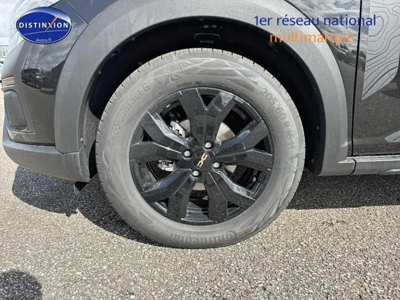 Gros plan sur la roue avant gauche noire nacrée métallisée du Dacia Jogger 2024 avec jante alu noire distinctive.