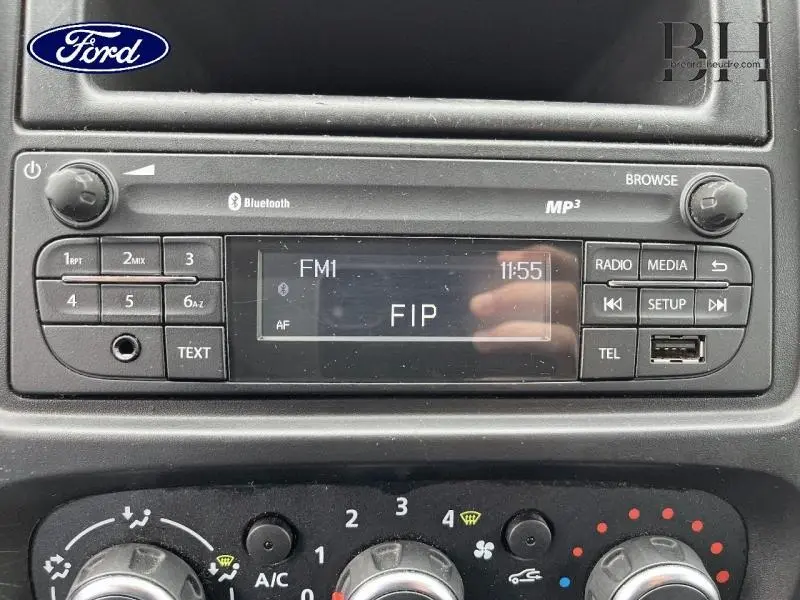 Gros plan sur la radio Bluetooth MP3 du tableau de bord d'un Renault Trafic blanc glacier, affichant la station FIP.