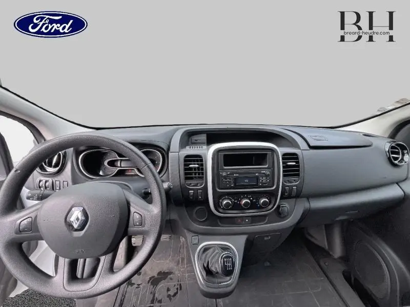 Vue intérieure du tableau de bord et volant noir du Renault Trafic Fourgon blanc, avec console centrale et levier de vitesses manuel.