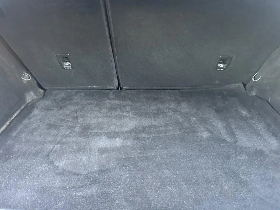 Coffre vide de la Renault Mégane IV Berline gris foncé vu de l'intérieur arrière, avec tapis de sol propre et fixations ISOFIX visibles.