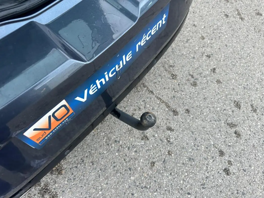 Gros plan sur l'attelage arrière d'une Renault Mégane IV gris foncé avec autocollant V.O Véhicule récent.