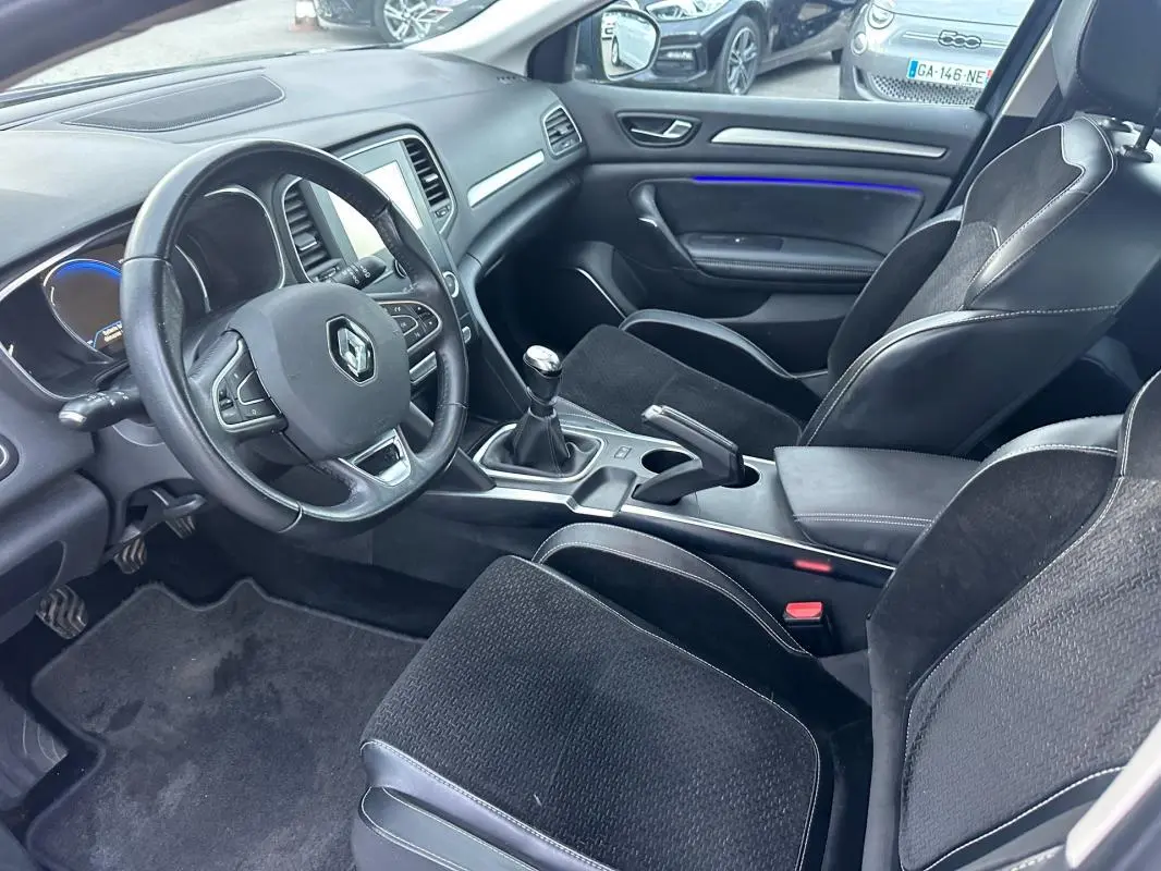 Intérieur de Renault Mégane IV TCe 130 Energy Intens 2016, vue côté conducteur, volant cuir et sièges tissu noir.