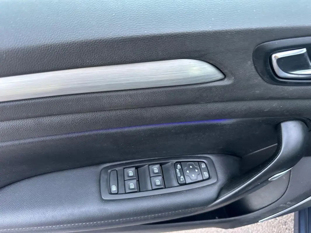 Panneau de porte côté gauche en cuir noir avec commandes électriques des vitres et rétroviseurs d'une Renault Mégane IV gris foncé.