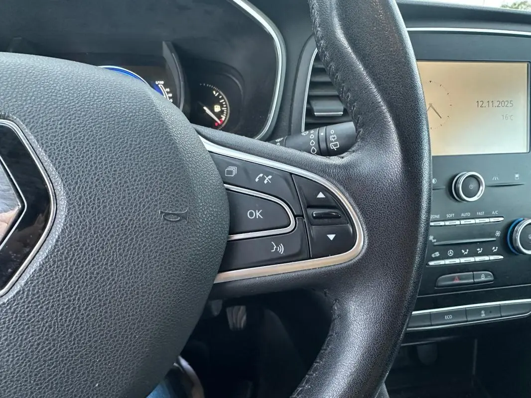 Gros plan sur le volant cuir noir de la Renault Mégane IV avec commandes multifonctions et tableau de bord partiel visible.