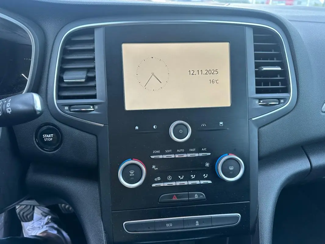 Vue rapprochée du tableau de bord noir de la Renault Mégane IV avec écran central et commandes de climatisation.