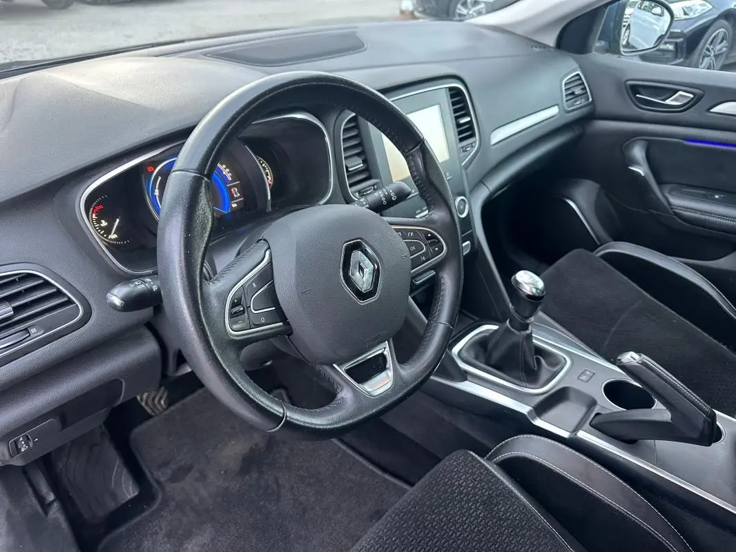 Intérieur de Renault Mégane IV TCe 130 gris foncé, vue côté conducteur sur volant cuir et levier de vitesse manuel.