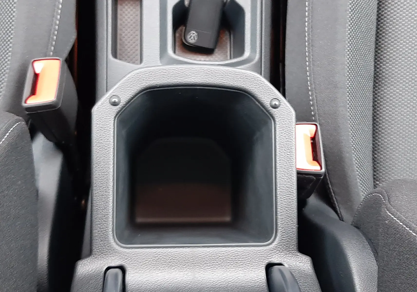 Vue plongeante sur la console centrale noire du Volkswagen T-Roc 2025 avec clé et sièges en tissu gris.