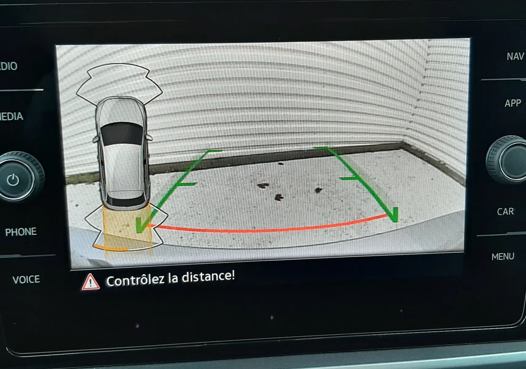 Vue écran caméra de recul du Volkswagen T-Roc gris pyrite métal, avec guidage vert et rouge pour le stationnement.
