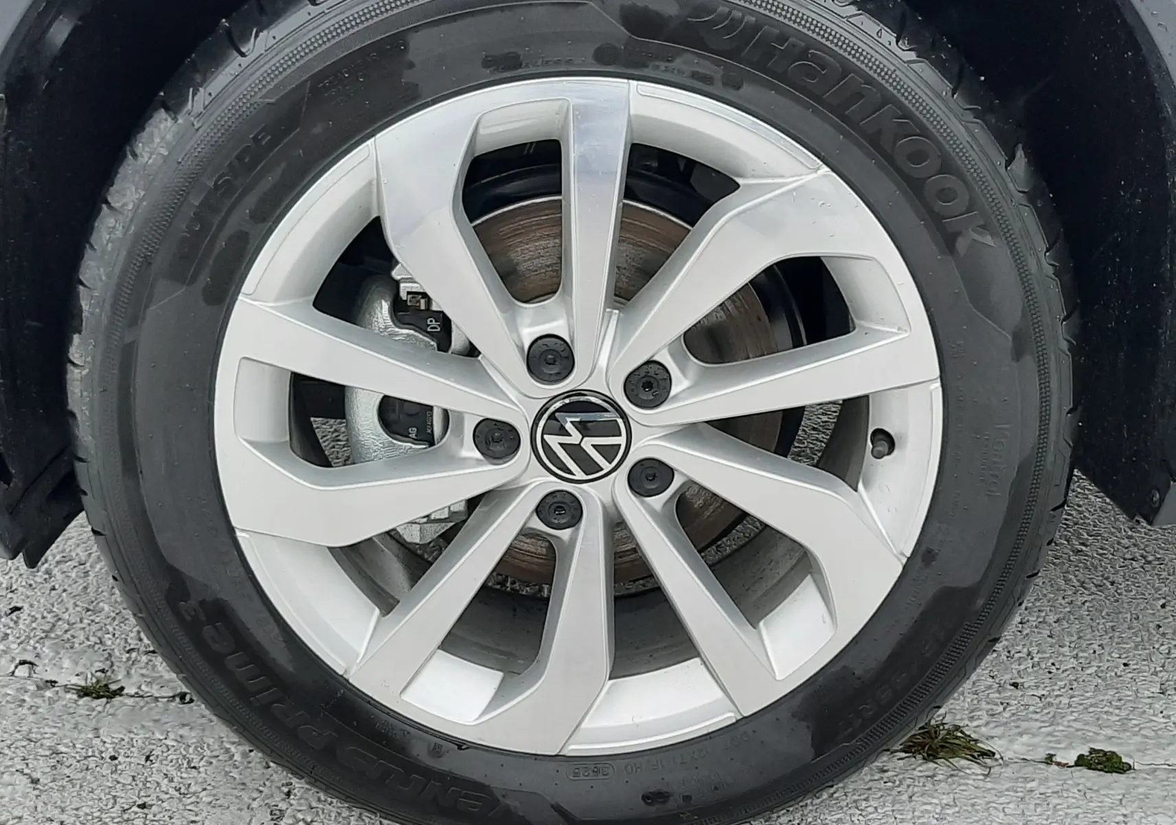 Gros plan sur la jante alliage argentée avec logo Volkswagen, pneu Hankook monté sur Volkswagen T-Roc gris pyrite.