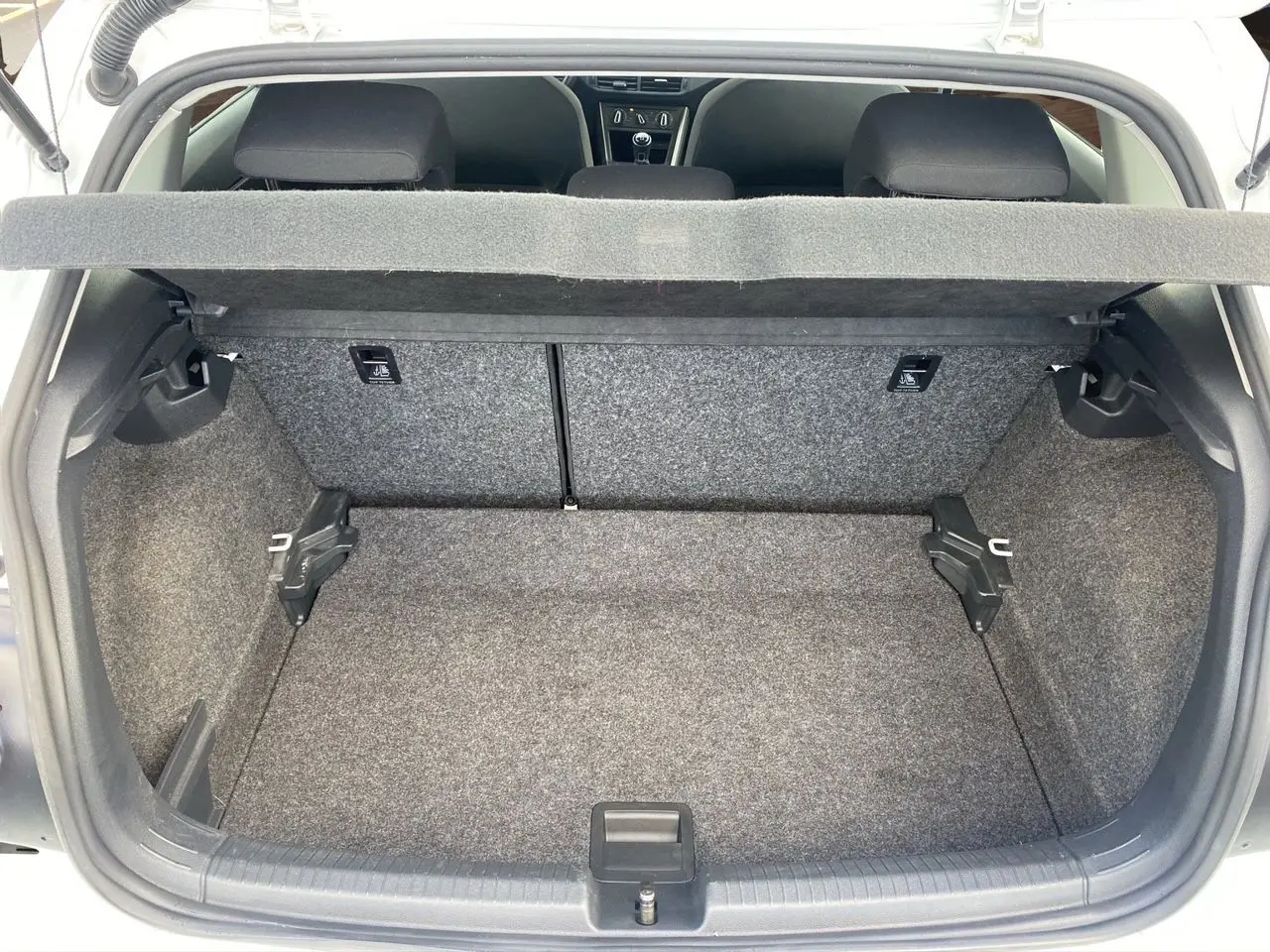 Vue intérieure du coffre ouvert d'une Volkswagen Polo blanche 2020, montrant l'espace de chargement et les sièges arrière noirs.