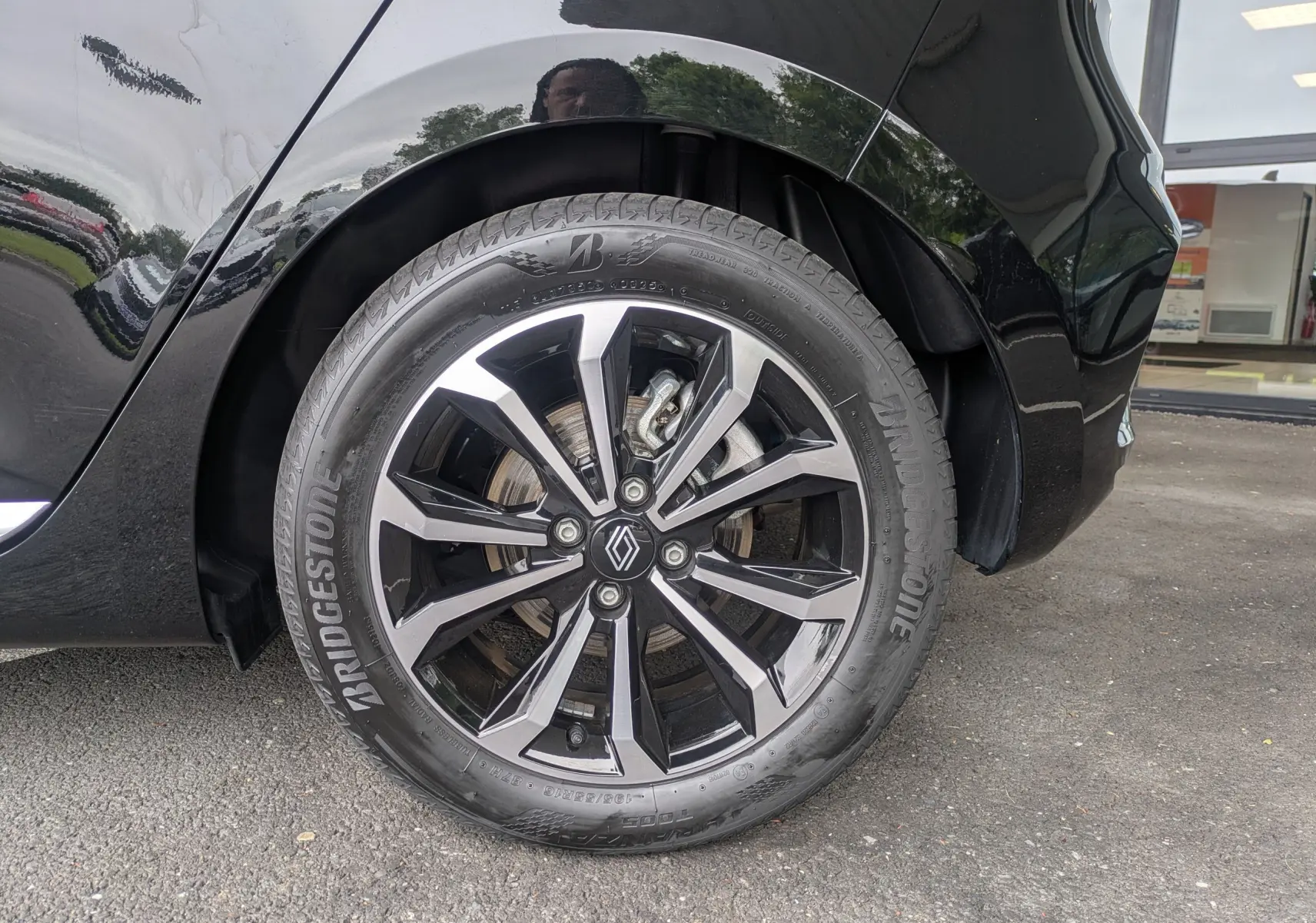 Gros plan sur la roue arrière droite noire étoile métal d'une Renault Clio 2025 avec jante alliage bicolore et pneu Bridgestone.