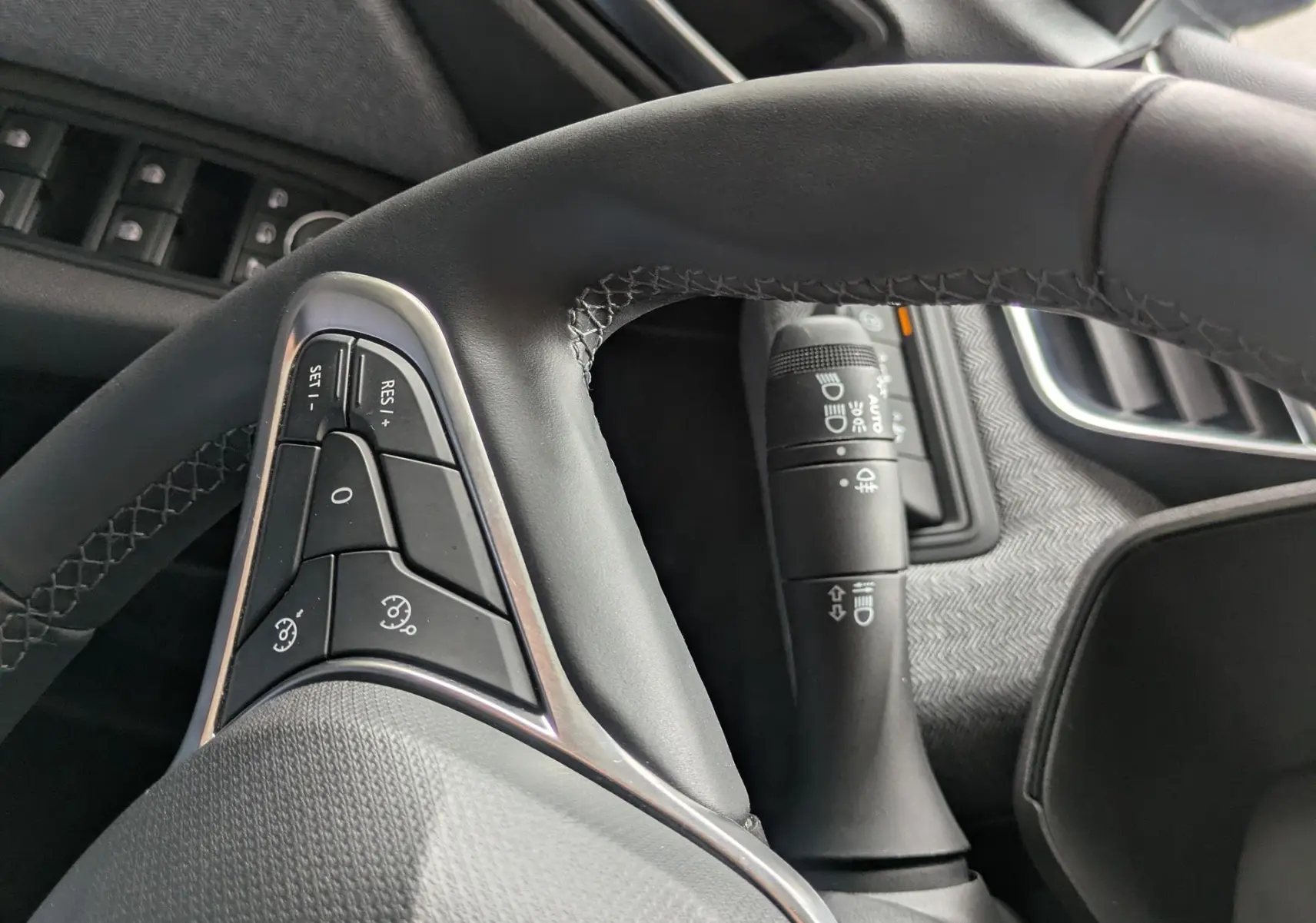 Vue rapprochée du volant cuir noir et des commandes au volant côté gauche dans l’habitacle gris noir d’une Renault Clio 2025.