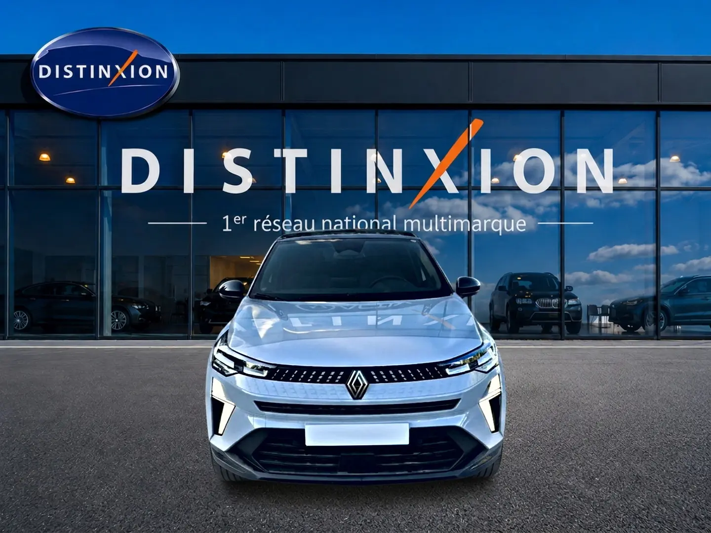 Vue frontale d'un Renault Captur gris rafale 2026 garé devant une vitrine avec logo Distinxion.