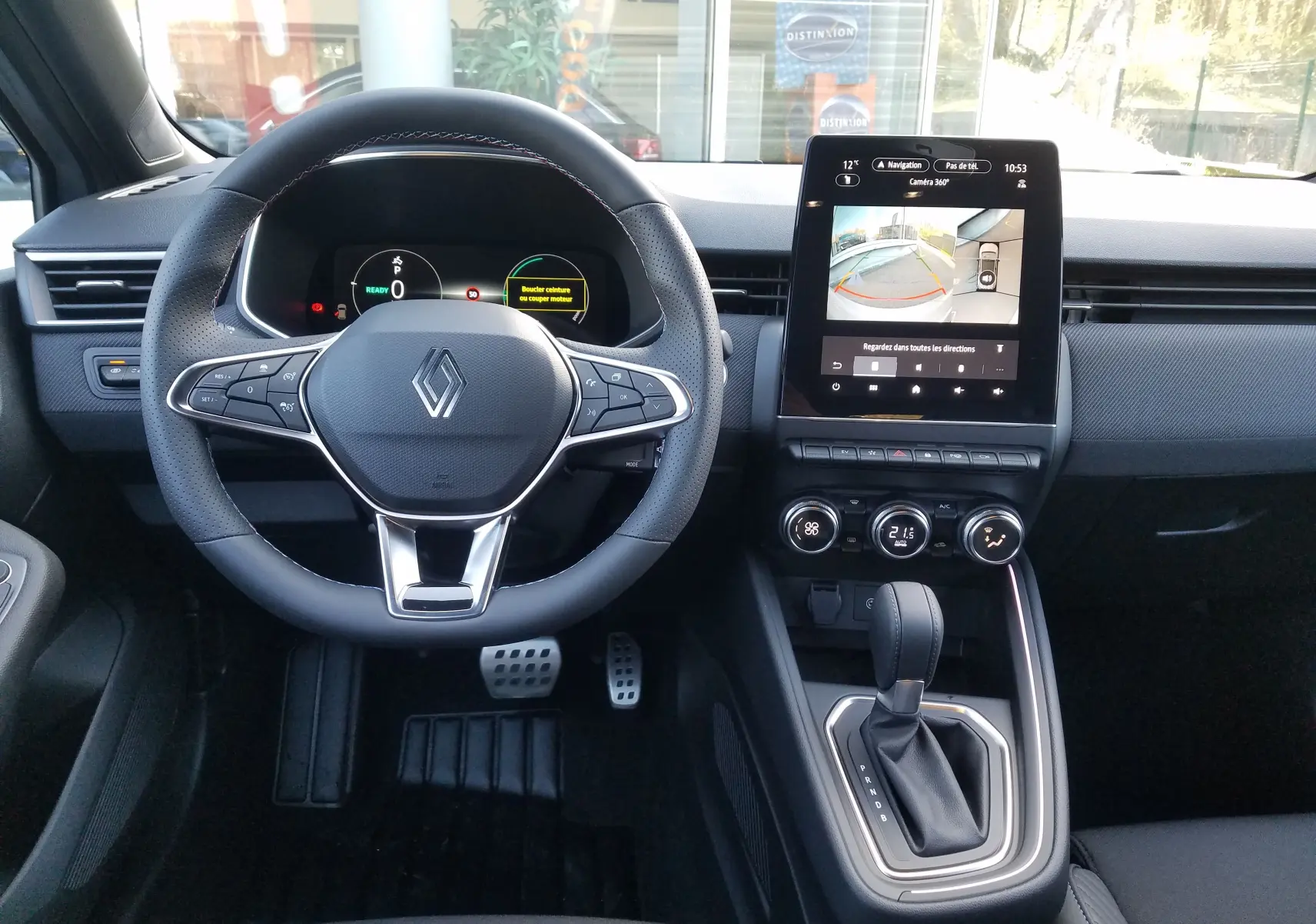 Vue intérieure avant du tableau de bord de la Renault Clio V hybride avec écran tactile et volant multifonction noir.