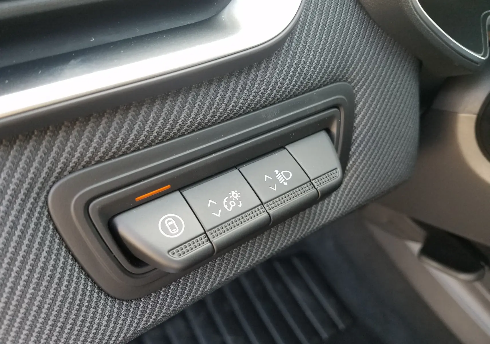 Gros plan sur les commandes de réglage des feux et du tableau de bord de la Renault Clio V hybride gris Rafale.