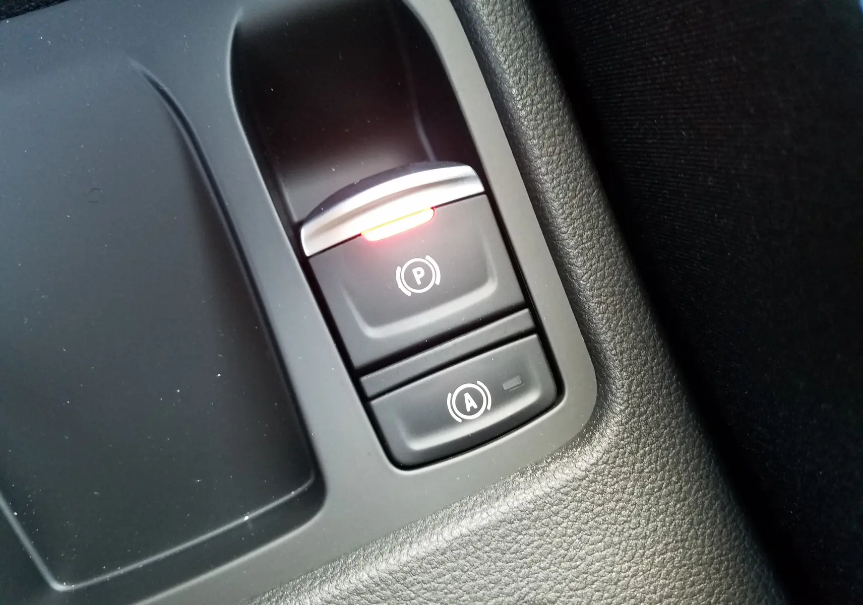 Gros plan sur les commandes du frein de parking assisté et du démarrage automatique dans la Renault Clio V gris Rafale.