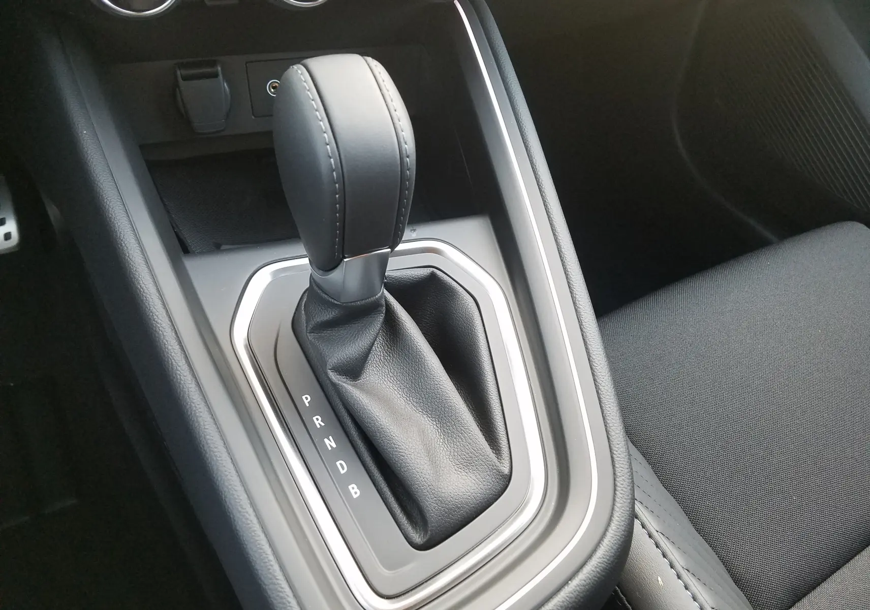 Le levier de boîte automatique en cuir noir de la Renault Clio V hybride, vue rapprochée de la console centrale.