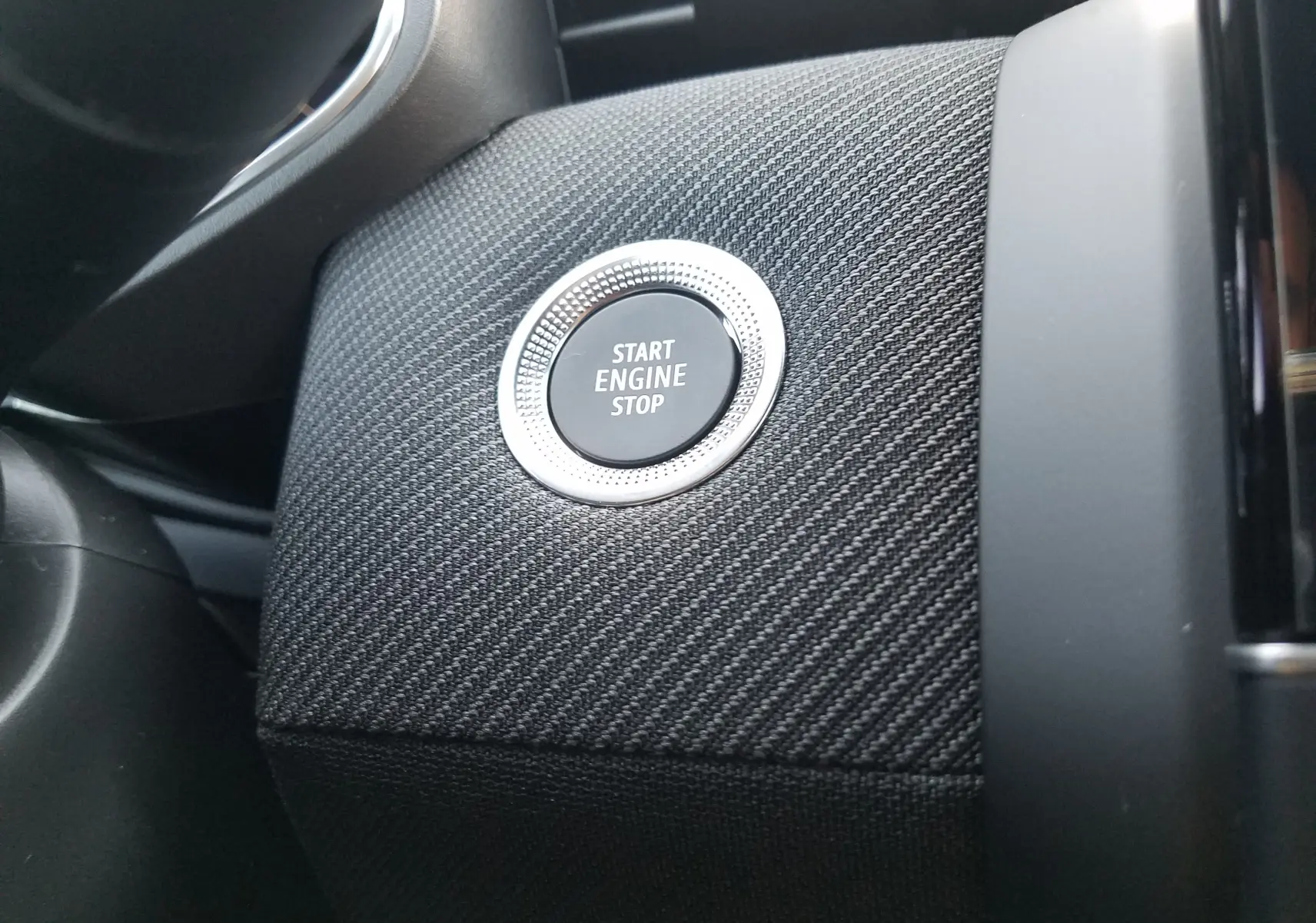 Bouton Start Engine Stop en gros plan sur tableau de bord texturé noir de la Renault Clio V hybride 2025.
