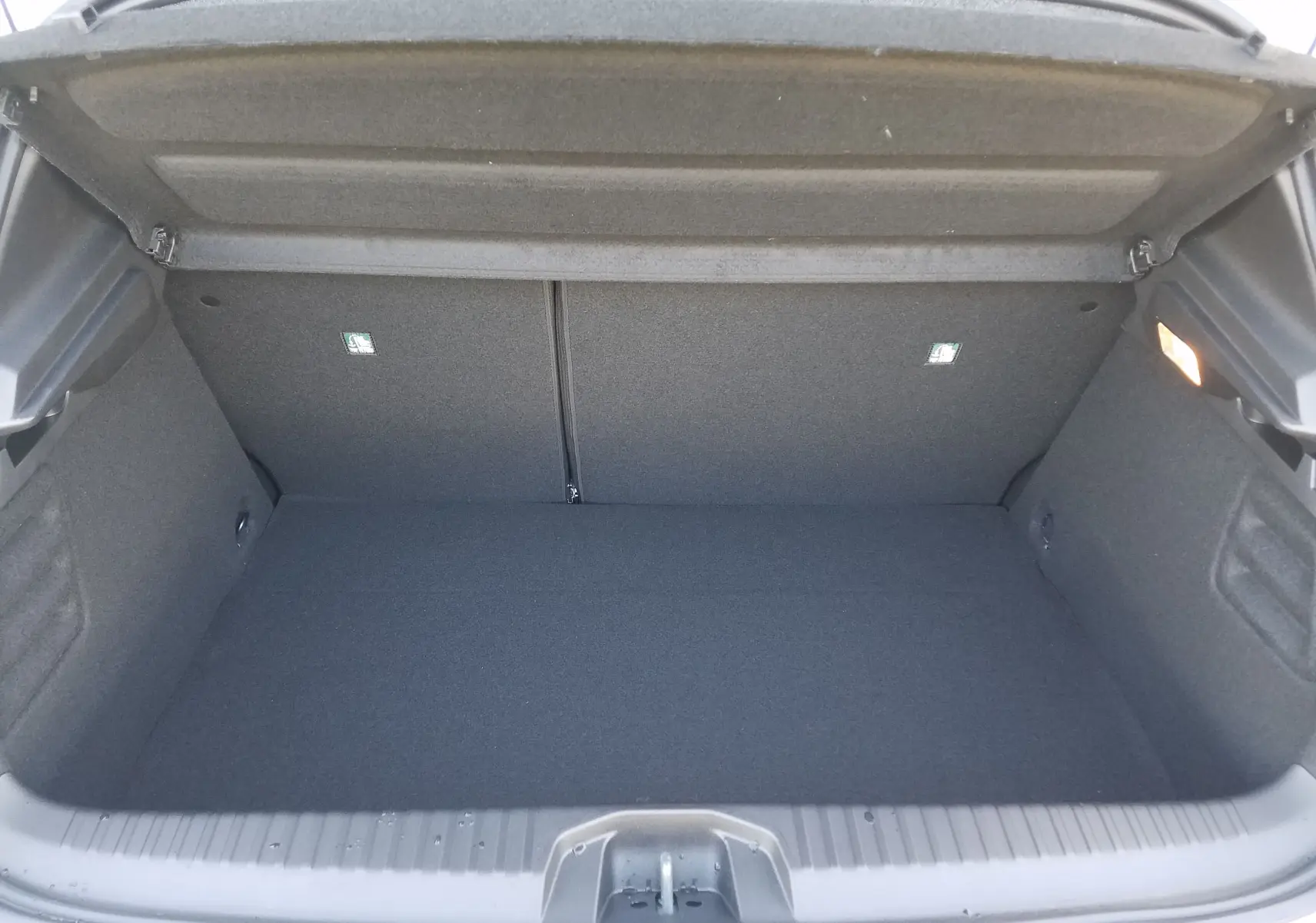 Coffre ouvert de la Renault Clio V hybride gris Rafale, montrant un espace de rangement propre et bien agencé.