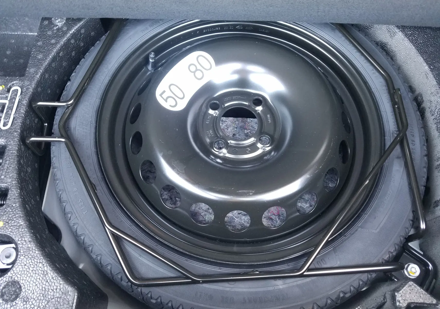 Roue de secours temporaire noire de la Renault Clio V 1.6E-TECH Hybride 145, vue en gros plan dans le coffre.