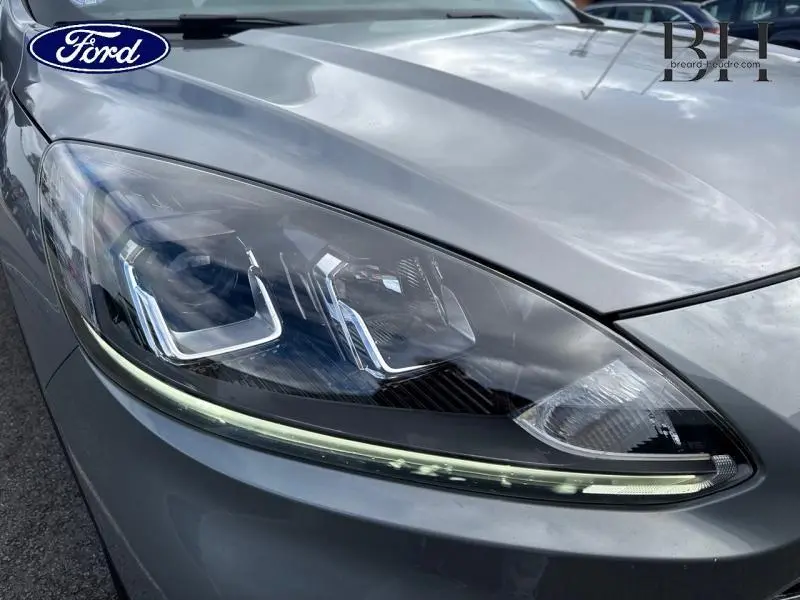 Gros plan sur le phare avant droit du Ford Kuga gris Solar métallisé avec LED distinctive et capot lisse.