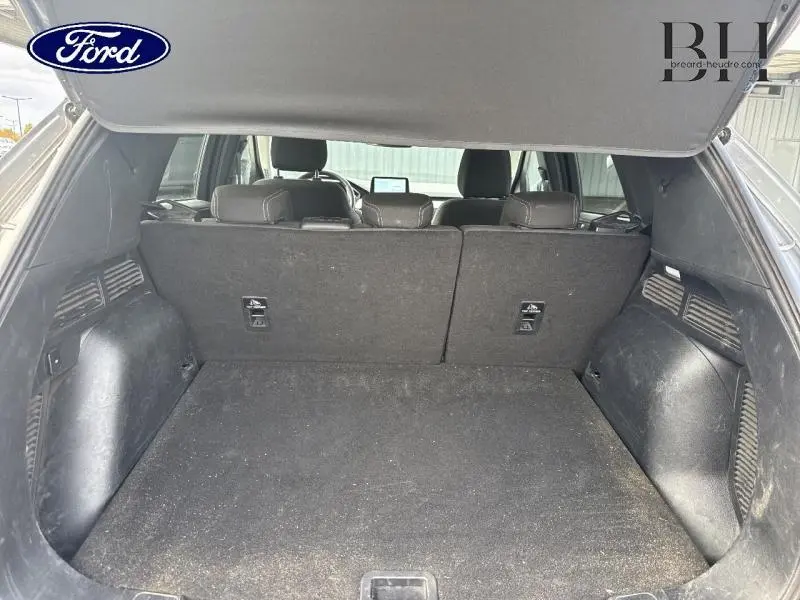 Coffre ouvert vu de l'arrière d'un Ford Kuga gris Solar, montrant la banquette arrière et l'espace de chargement.