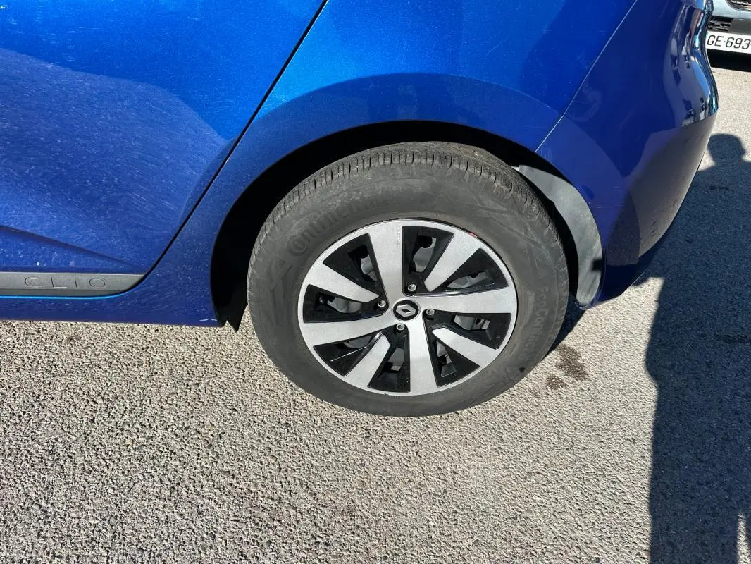 Gros plan sur la roue arrière droite d'une Renault Clio bleu foncé 2023 avec jante alliage au design moderne.