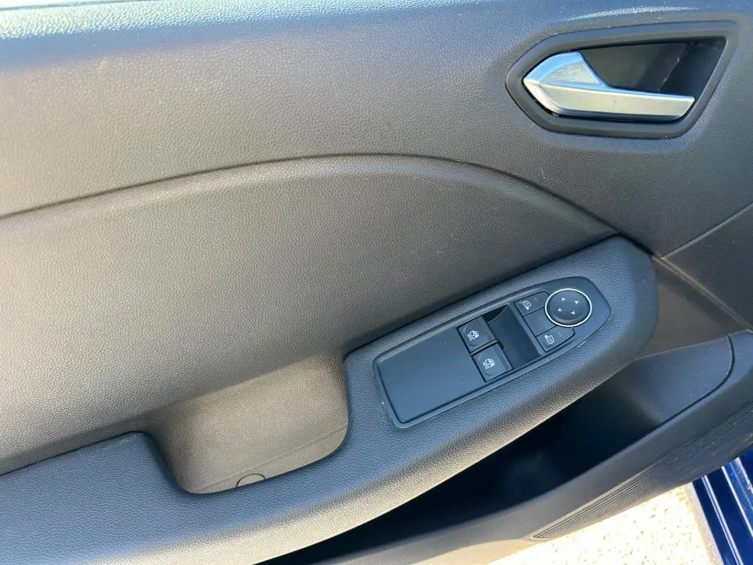 Panneau de porte côté conducteur de Renault Clio bleu foncé 2023 avec commandes électriques des vitres et rétroviseurs.
