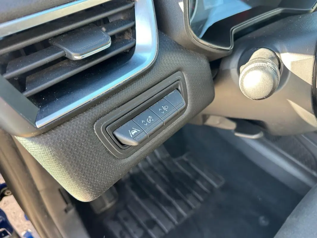 Gros plan sur les commandes d'aide à la conduite à gauche du volant d'une Renault Clio bleu foncé 2023.