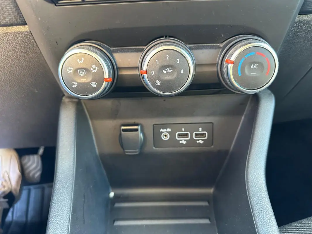 Gros plan sur les commandes de climatisation manuelle et les ports USB d'une Renault Clio V TCe 90 bleu foncé de 2023.