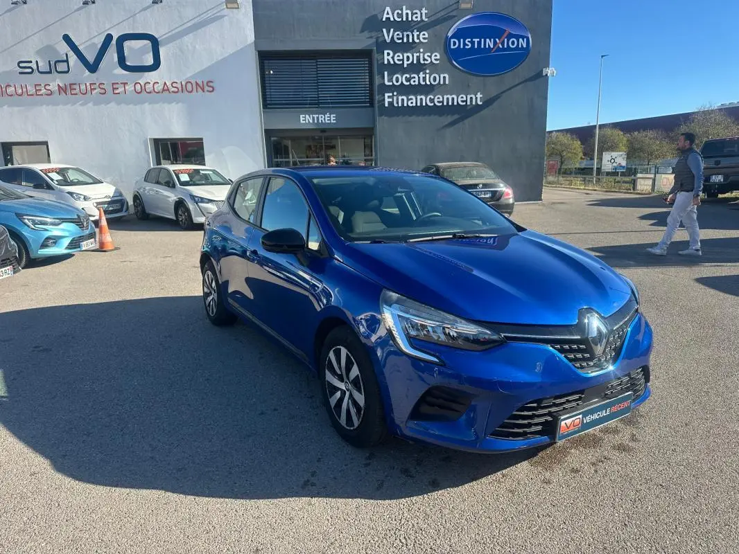 Renault Clio V TCe 90 Equilibre bleu foncé vue 3/4 avant droit sur parking devant concessionnaire