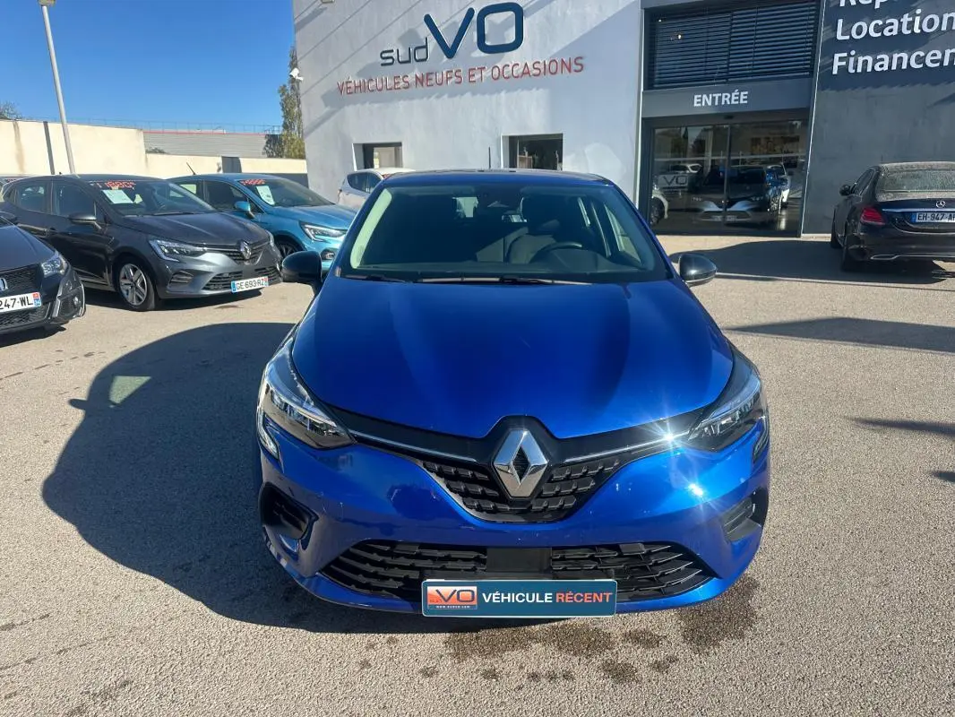 Renault Clio V TCe 90 bleu foncé vue de face, avec calandre noire et logo Renault brillant au soleil.