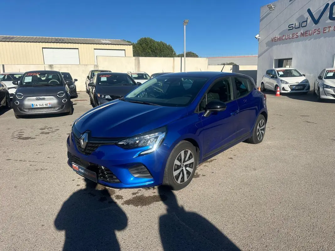 Renault Clio V TCe 90 bleu foncé vue 3/4 avant droit sur parking ensoleillé avec antenne requin visible