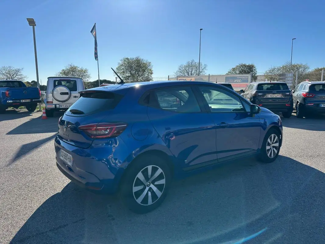 Renault Clio bleu foncé vue 3/4 arrière côté droit, avec antenne requin et feux arrière LED distinctifs.