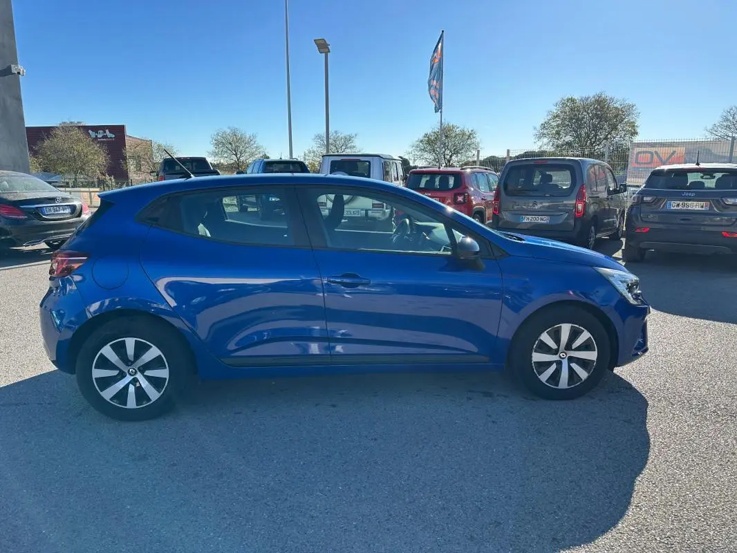 Profil côté gauche d'une Renault Clio V TCe 90 Équilibre bleu foncé garée en extérieur par temps ensoleillé.