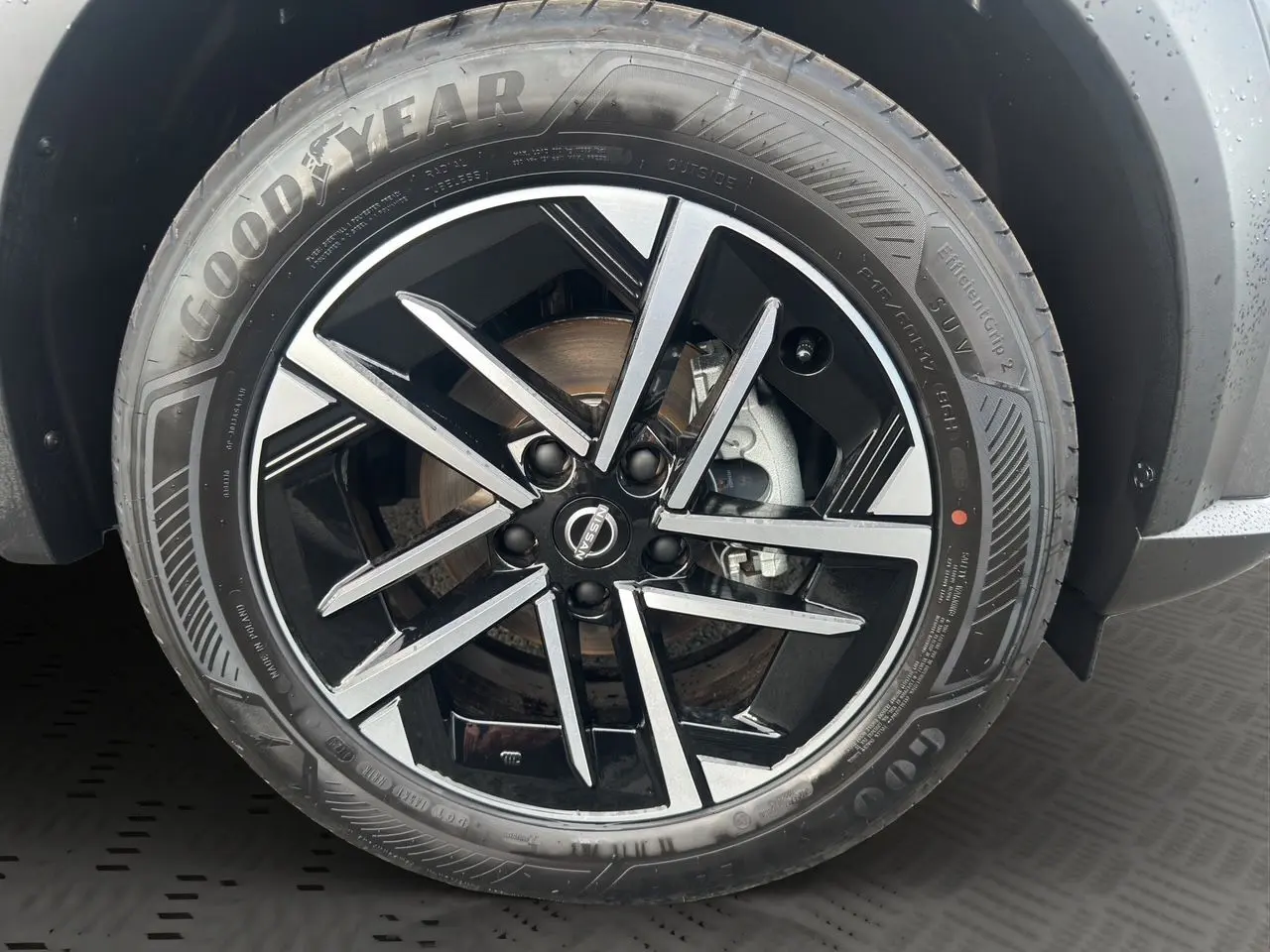 Gros plan sur la jante noire et argentée du Nissan Juke 1.6 Hybrid 2025 en gris squale, avec pneu Goodyear visible.