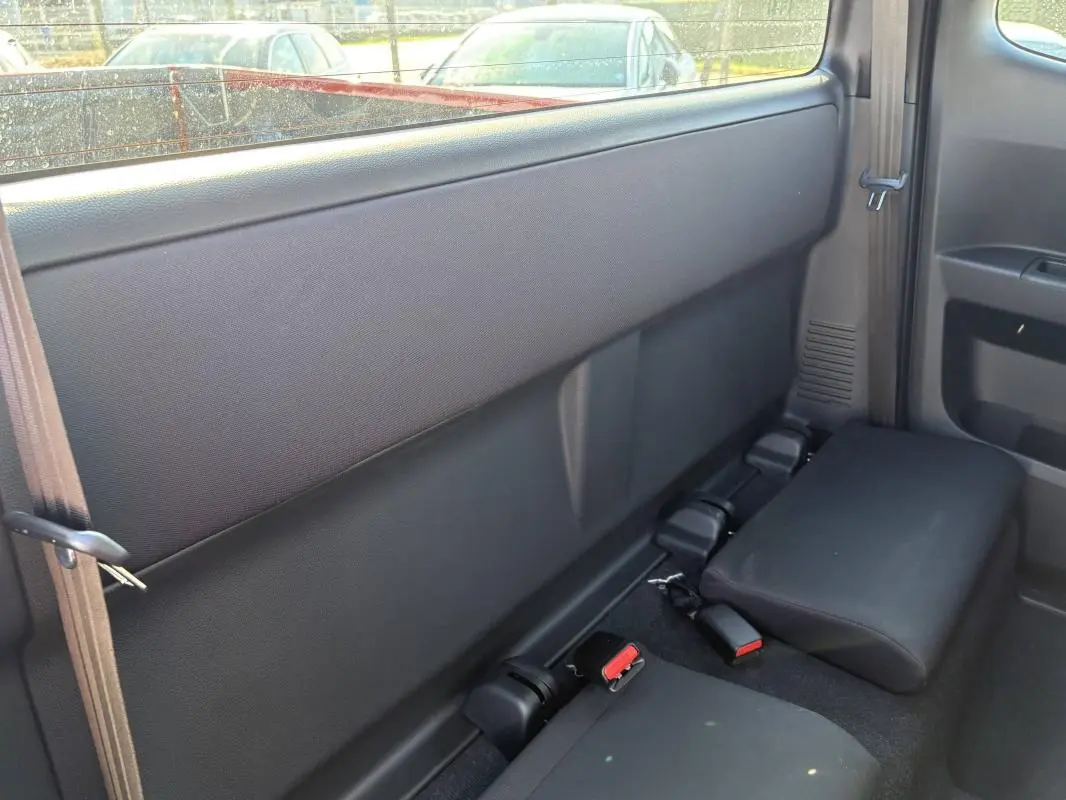 Vue intérieure arrière côté droit du pick-up Isuzu D-MAX 2026, sièges arrière rabattus en tissu noir.