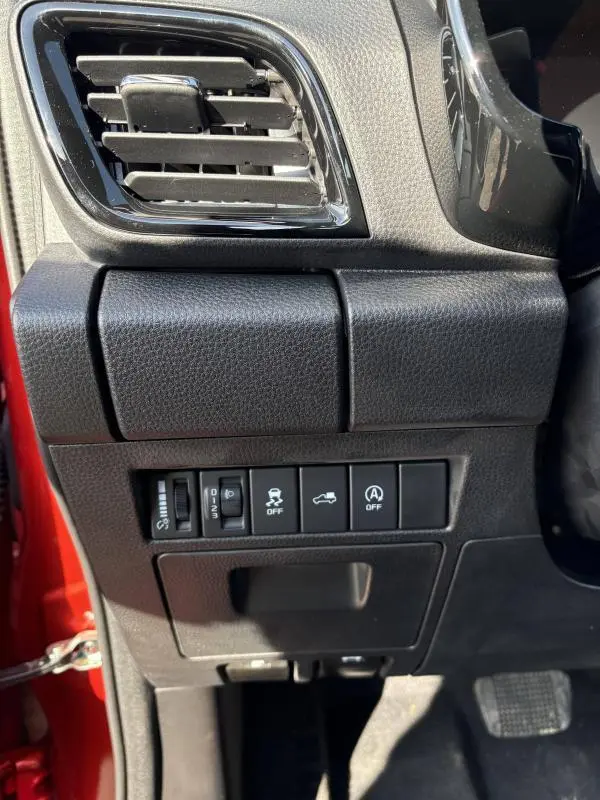 Vue rapprochée côté gauche du tableau de bord noir de l'Isuzu D-MAX orange 2026 avec commandes et sortie d'air.