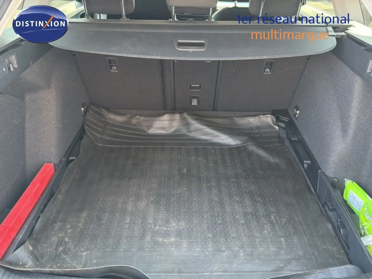 Coffre ouvert vu de l'arrière d'une Volkswagen Golf SW 2026 bleu Anemone, avec tapis de protection noir et rangements latéraux.