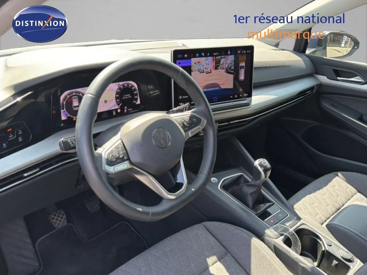 Vue intérieure côté conducteur de la Volkswagen Golf SW 1.5 TSI 2026, avec tableau de bord numérique et levier de vitesse manuel.